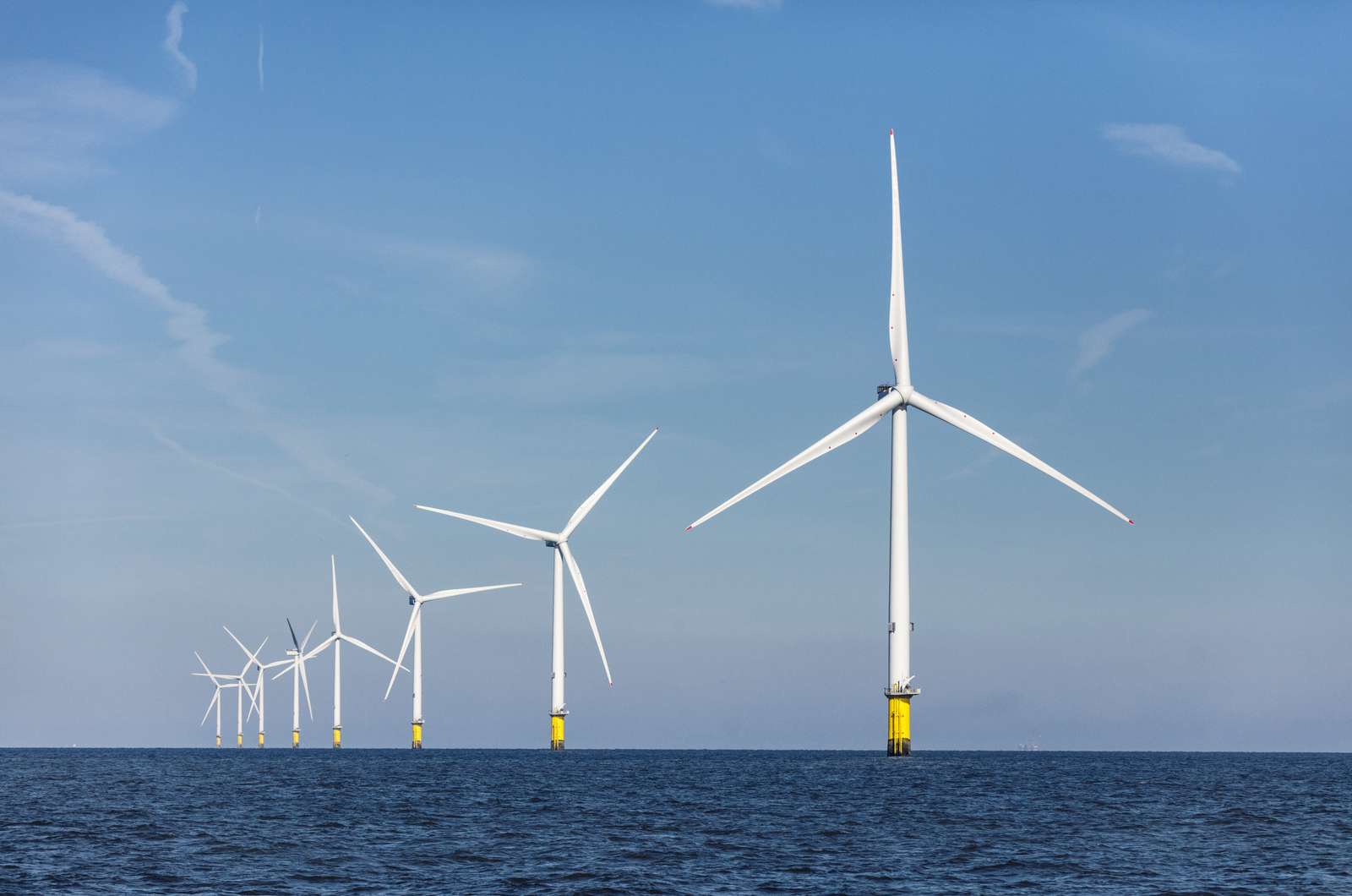 Image of rotating offshore wind turbines on a sunny day